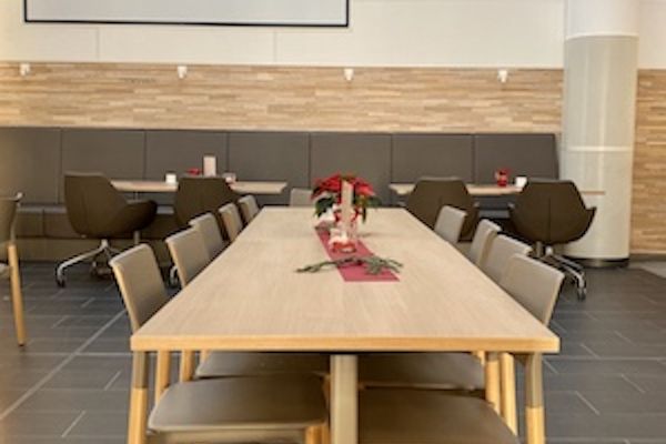 Tisch mit Stühlen im Vordergrund und große weiße Wand im Hintergrund und integrierter Beamerwand